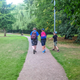 Three children are walking through the park, chatting and playing Pokemon GO.